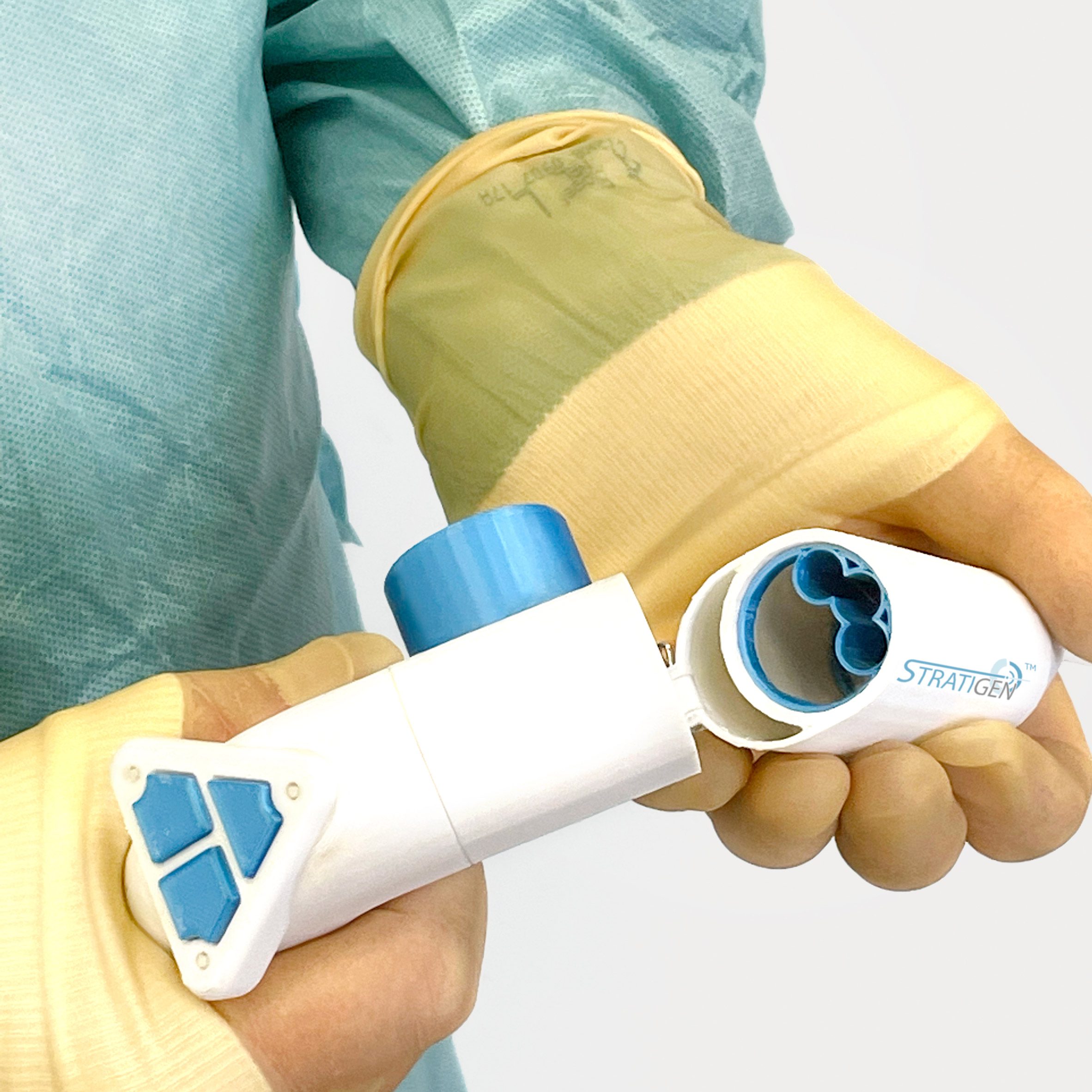 A photograph of a person's hands, in yellow gloves, handing a medical device that is white and blue.