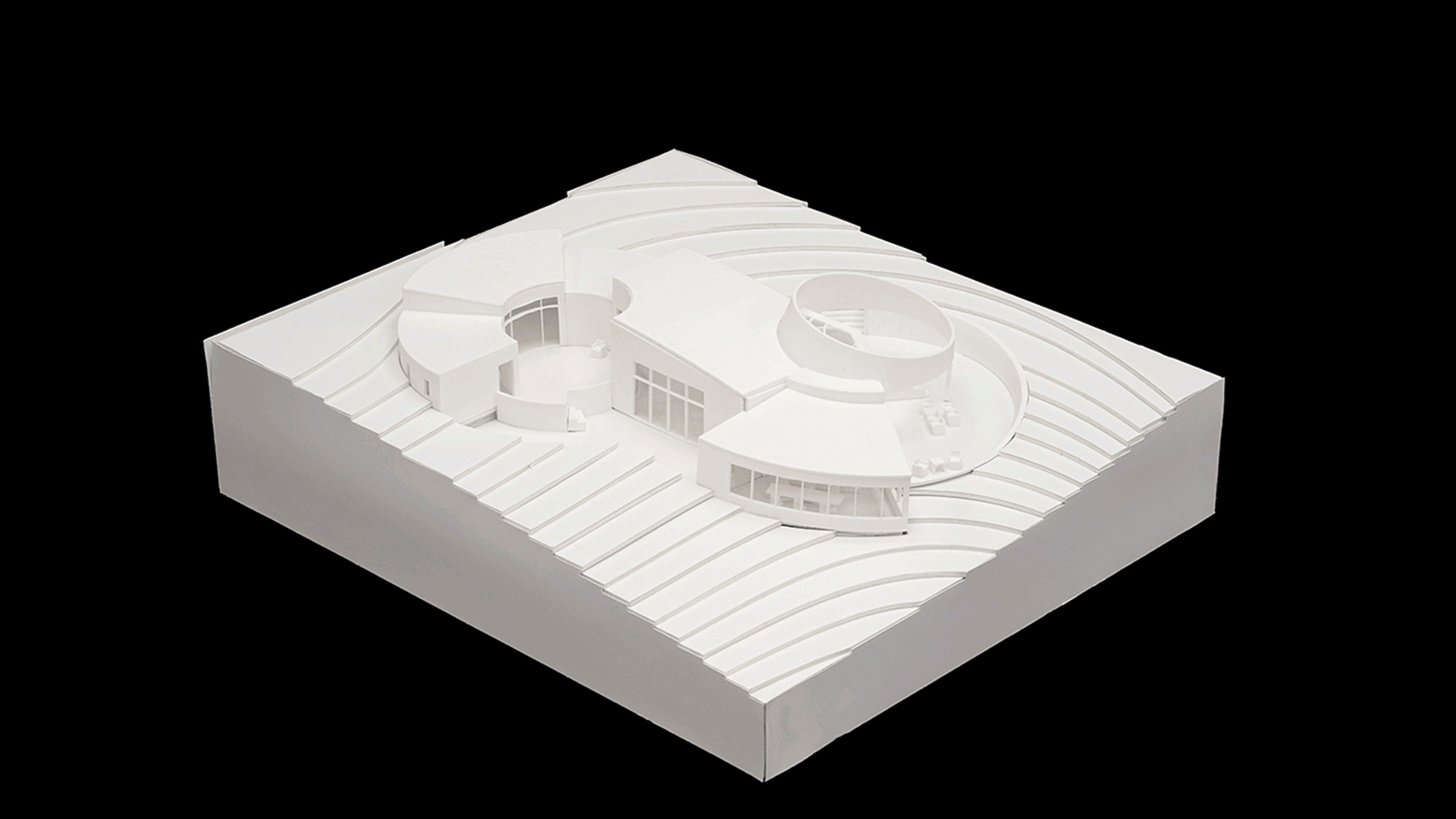 A photograph of a white architectural model against a black background.