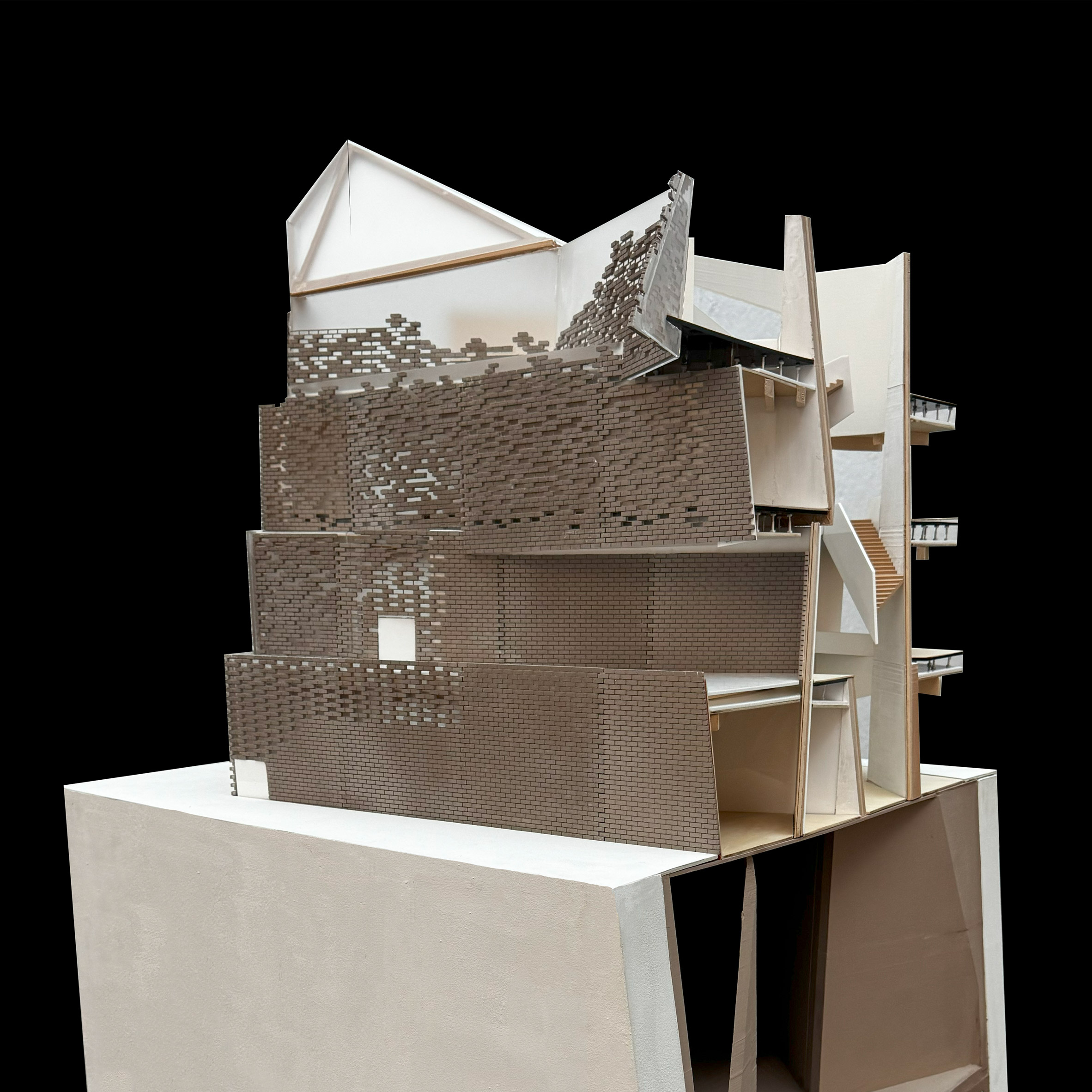 A photograph of an architectural model in tones of beige and white, against a black background.