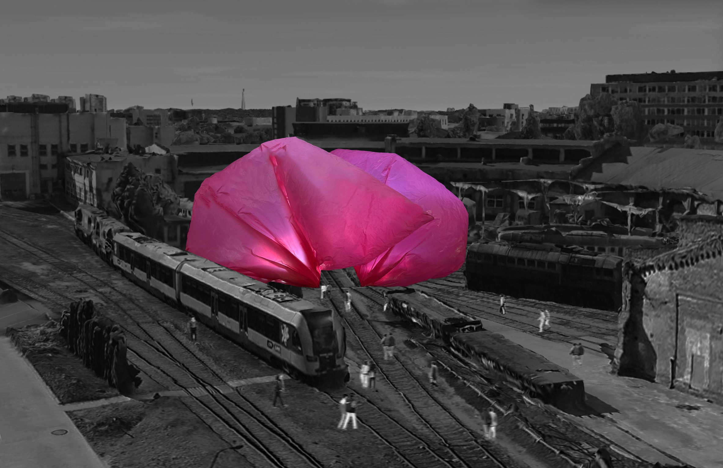 A black and white photograph of a train track with a large inflated pink structure over it.