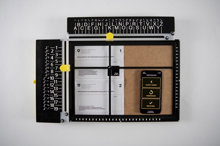 A photograph of a manual device to help blind people vote - it is black with white letters ad numbers on it, both in braille and latin, along with yellow toggles to navigate the device.