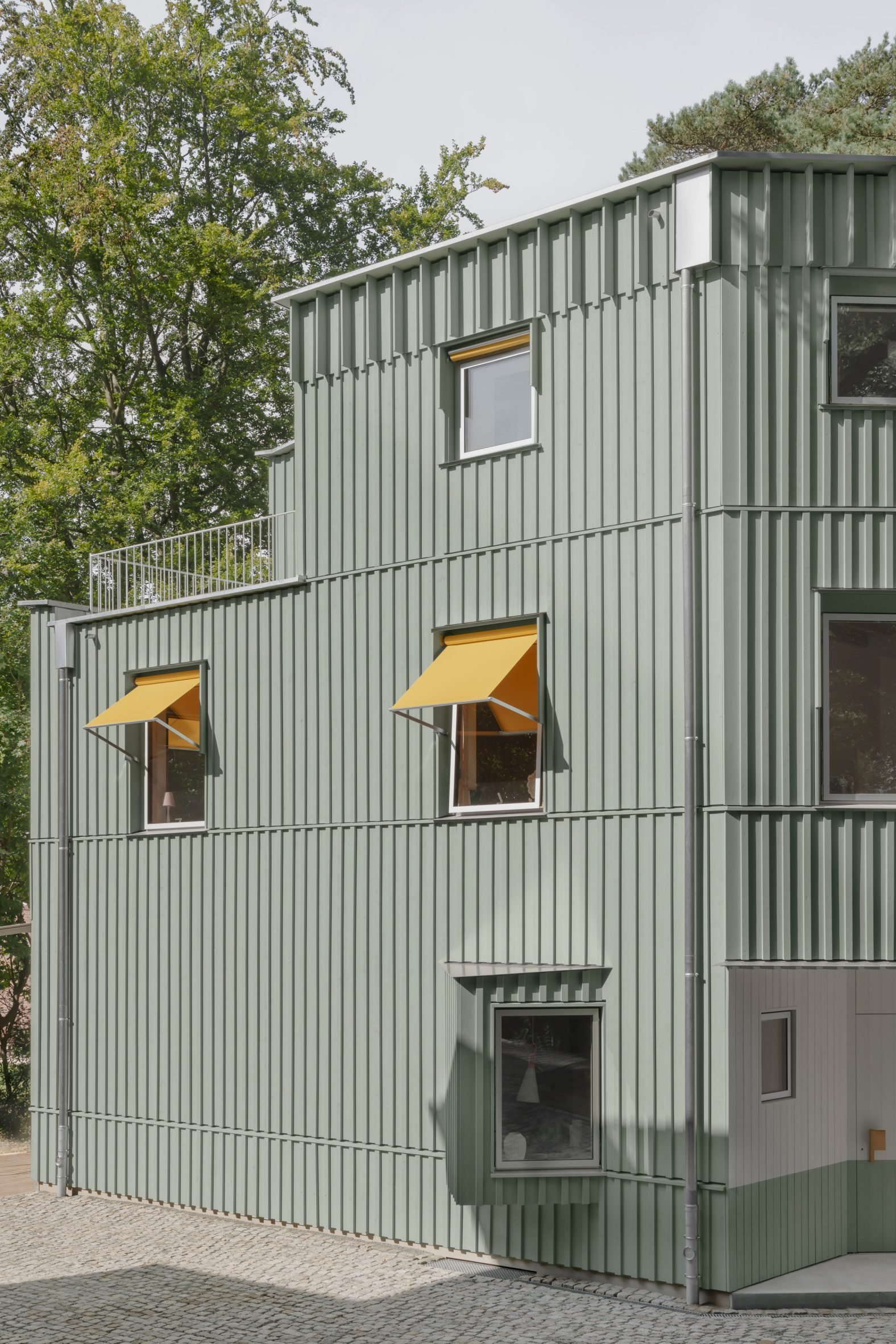 Sage green facade of duplex by NOTO