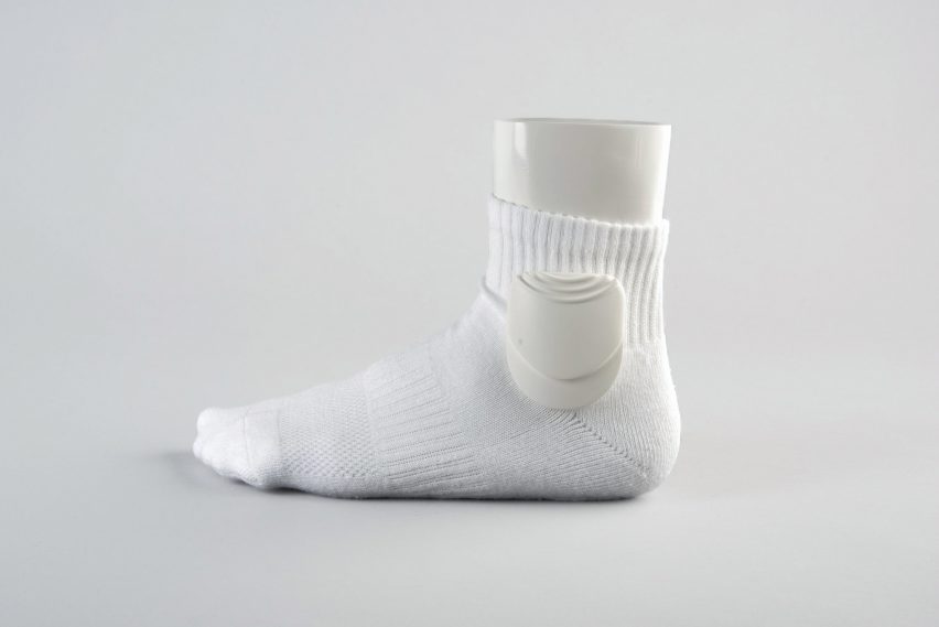 A photograph of a foot mannequin with a white sock on it against a grey backdrop.