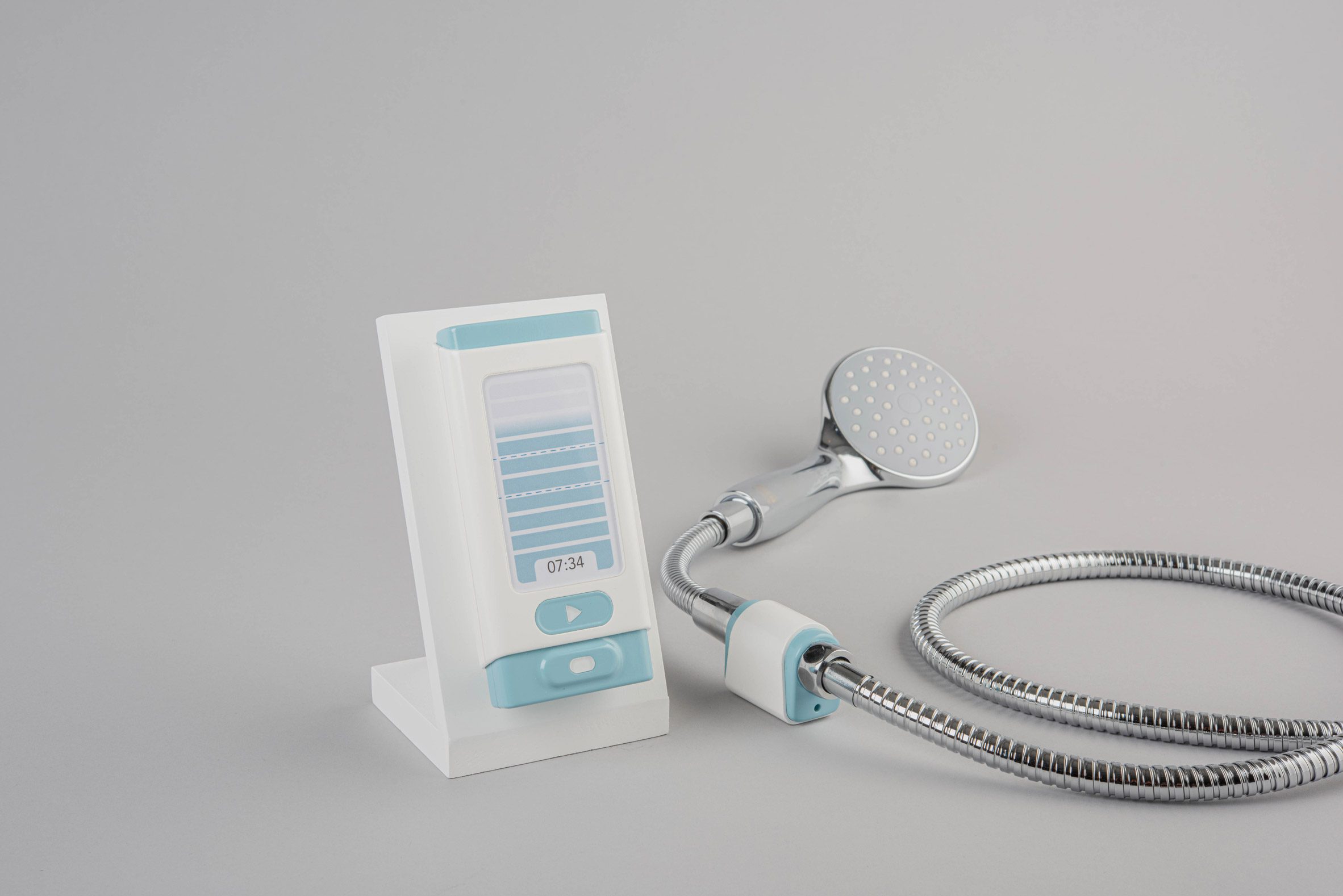 A photograph displaying a white and blue device alongside a silver showerhead, against a grey backdrop.