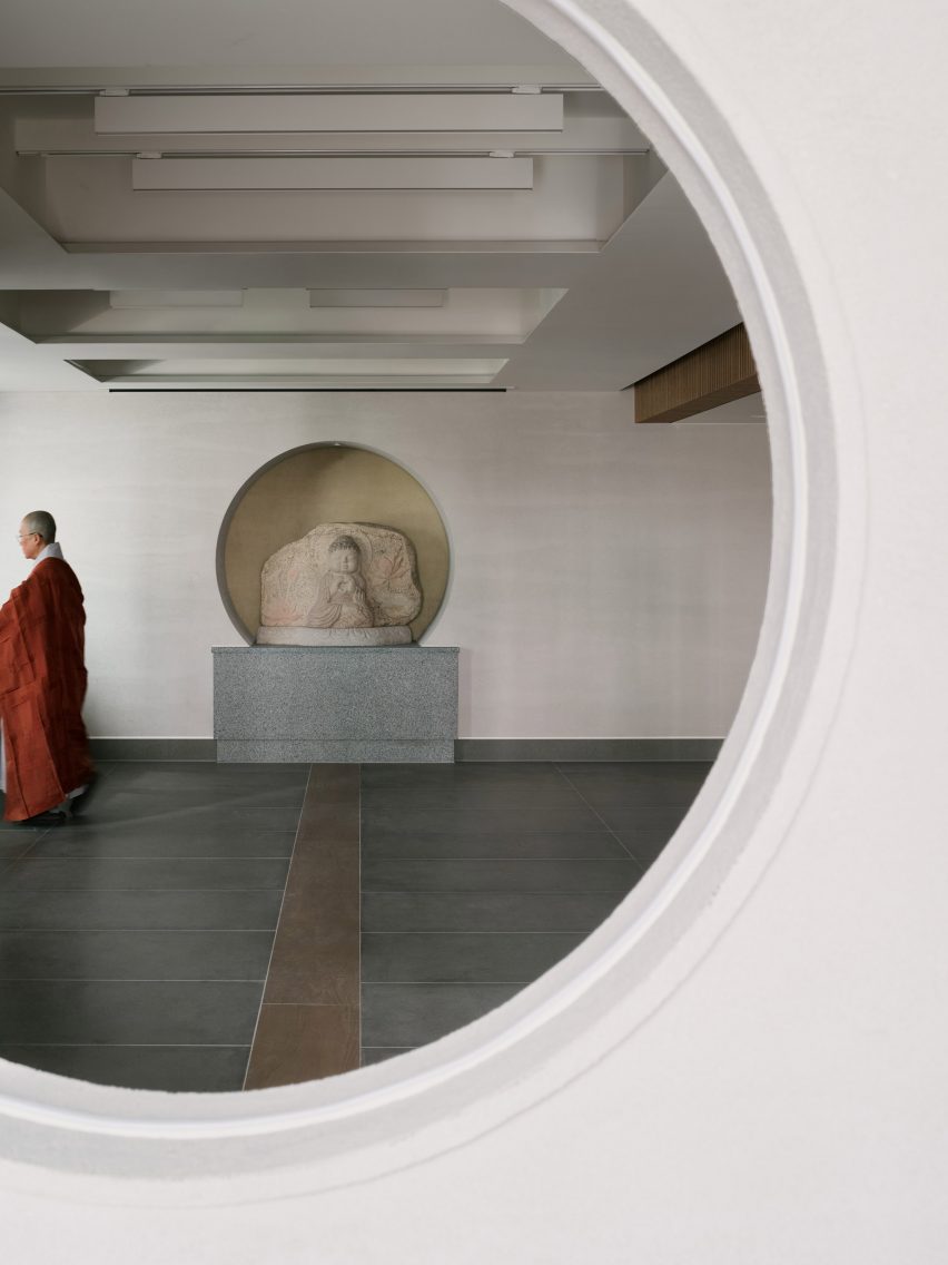 Porthole window looking through to buddha statue