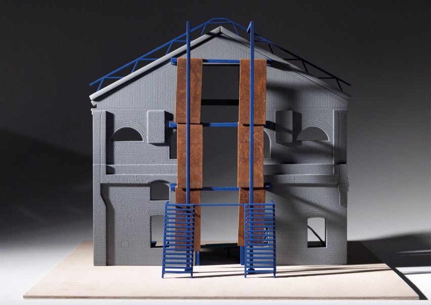 A photograph of an architectural model, in tones of grey, brown and blue, against a black backdrop.