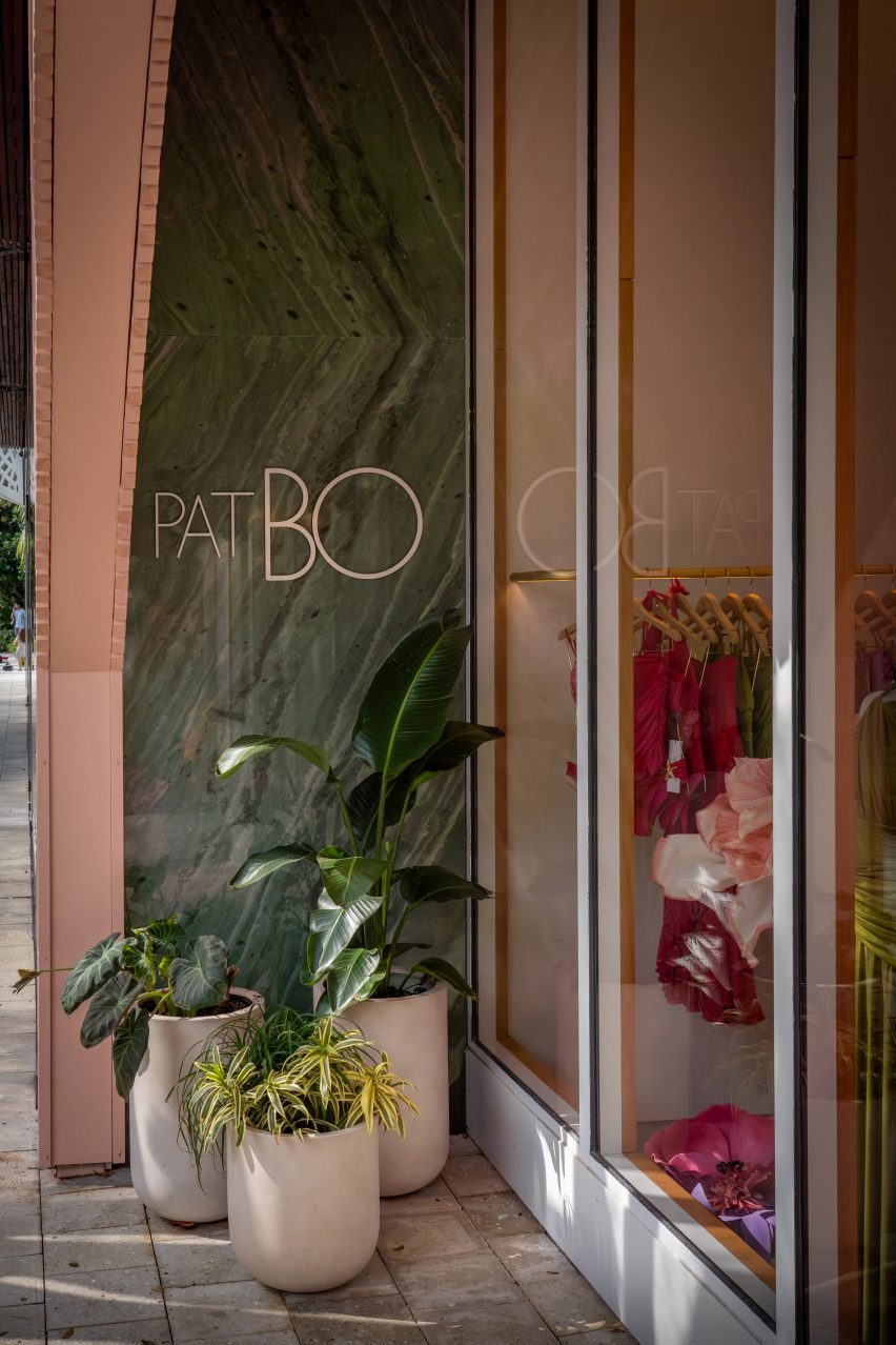 Green marble wall beside a shop window, with plants in front