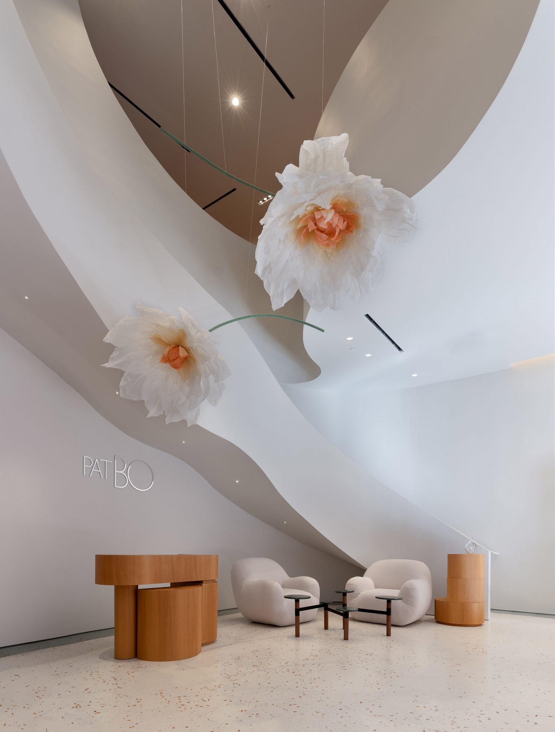 A ribbon-like staircase circling oversized silk flowers by Hana Form