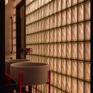 Glass bricks dividing bathroom and grey wash basin with red legs