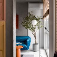 Blue sofa and orange coffee table in apartment by Dihome