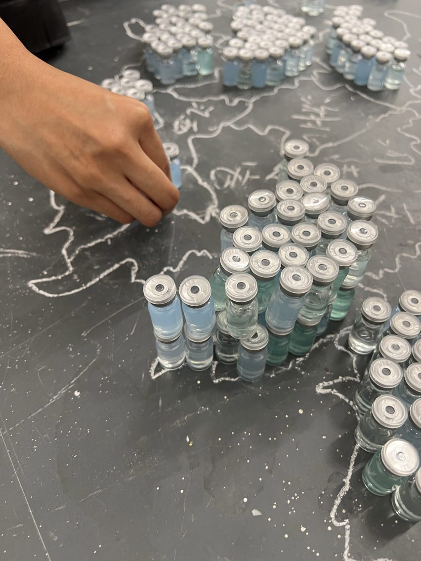 A photograph of a person handling small glass vessels with blue-coloured liquid inside.