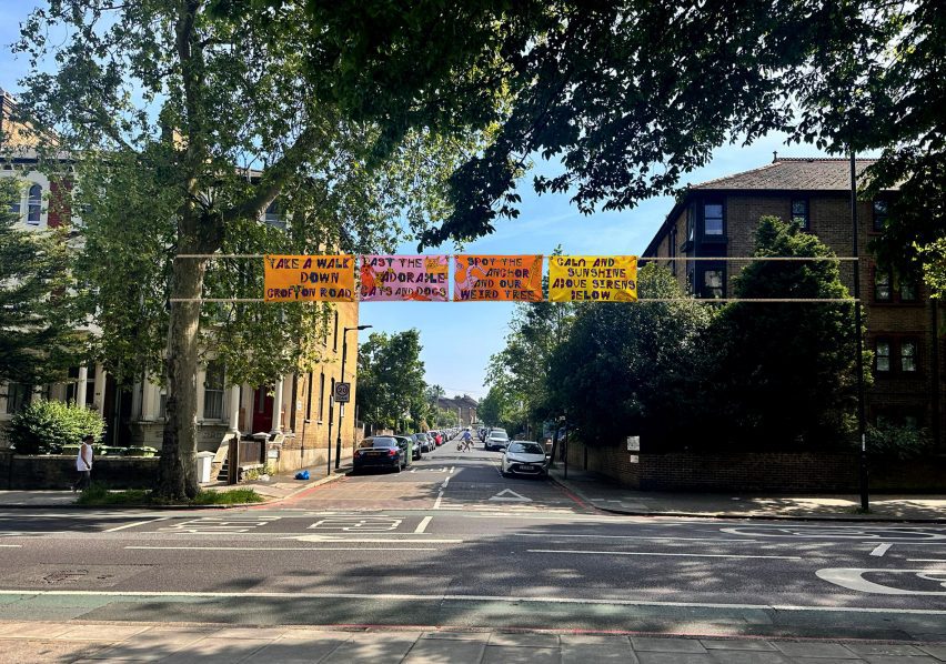 A photograph of a street with banners hung above it in tones of orange, yellow and pink