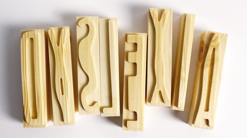 A photograph of wooden letterpress blocks displaying various characters from a custom typeface