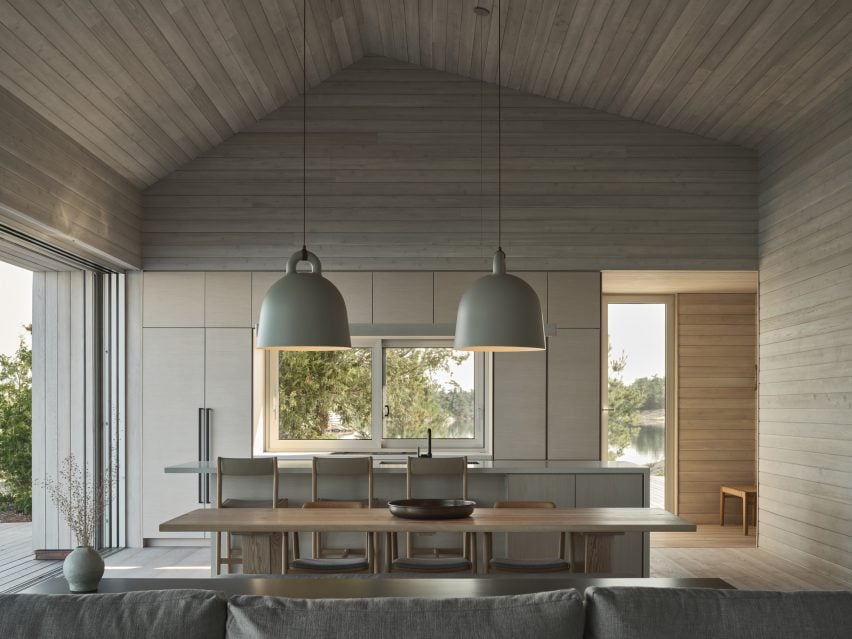 Open-plan kitchen and dining area clad in whitewashed cedar boards