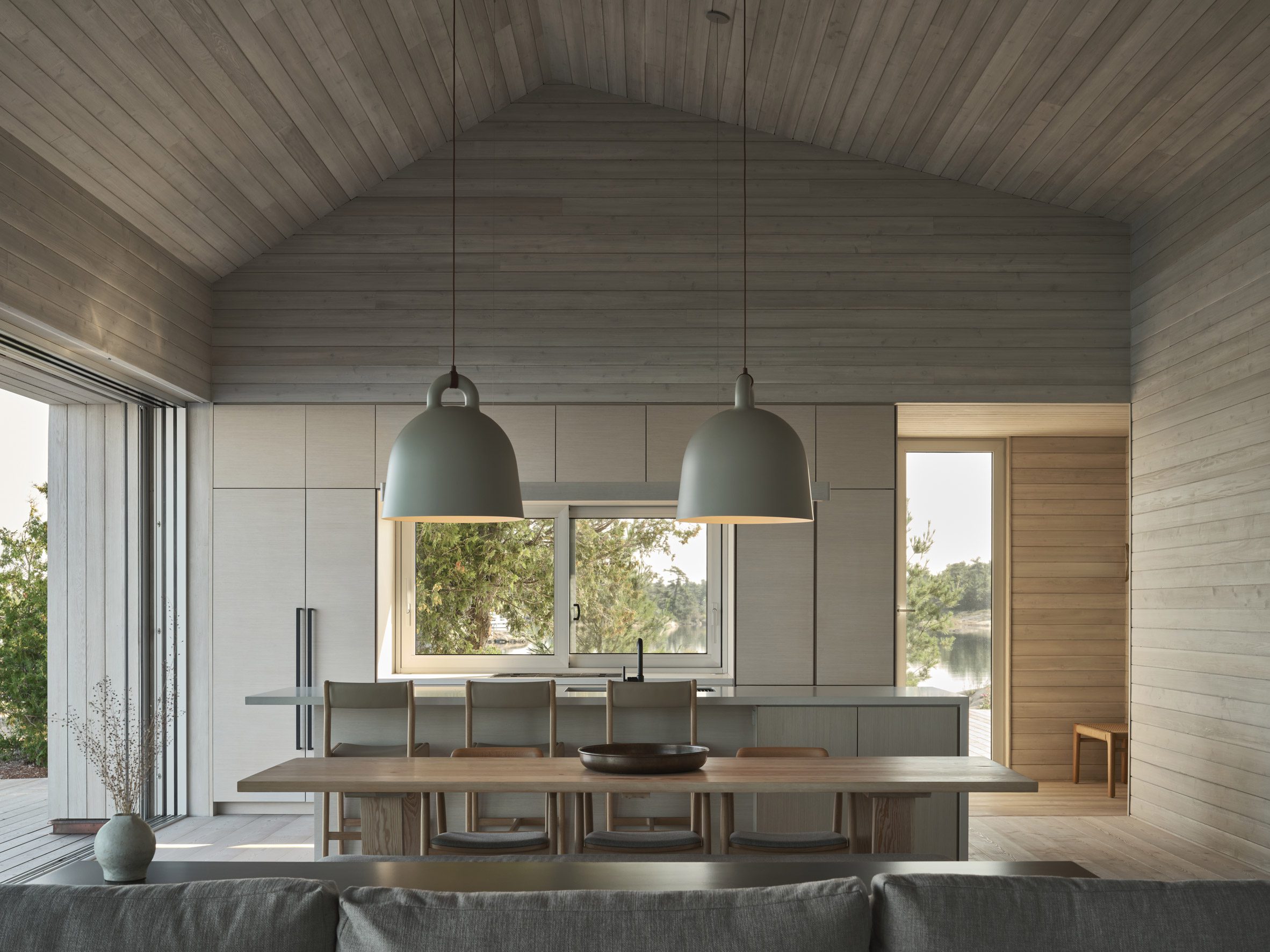 Open-plan kitchen and dining area clad in whitewashed cedar boards