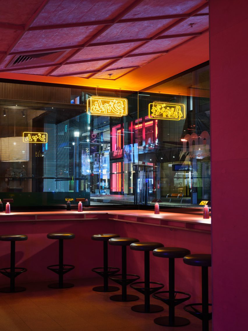 Stools in front of a window in a pink-toned bar