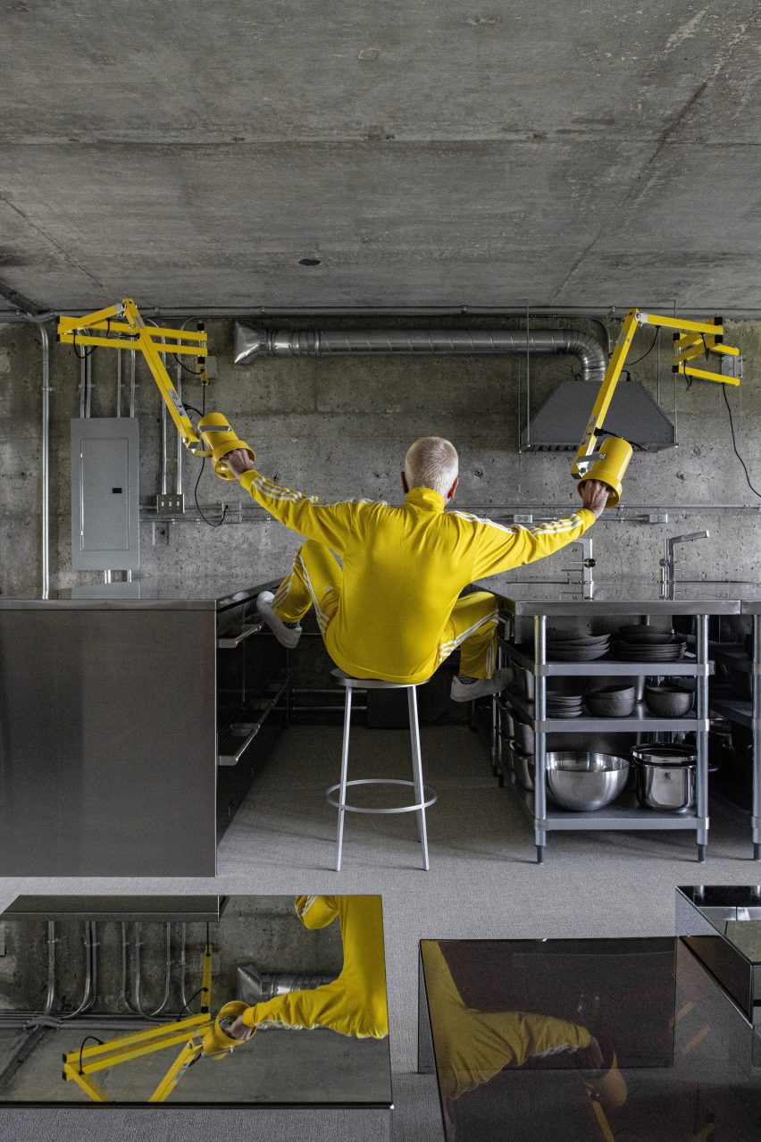 Man in a yellow tracksuit holding on to yellow lamps