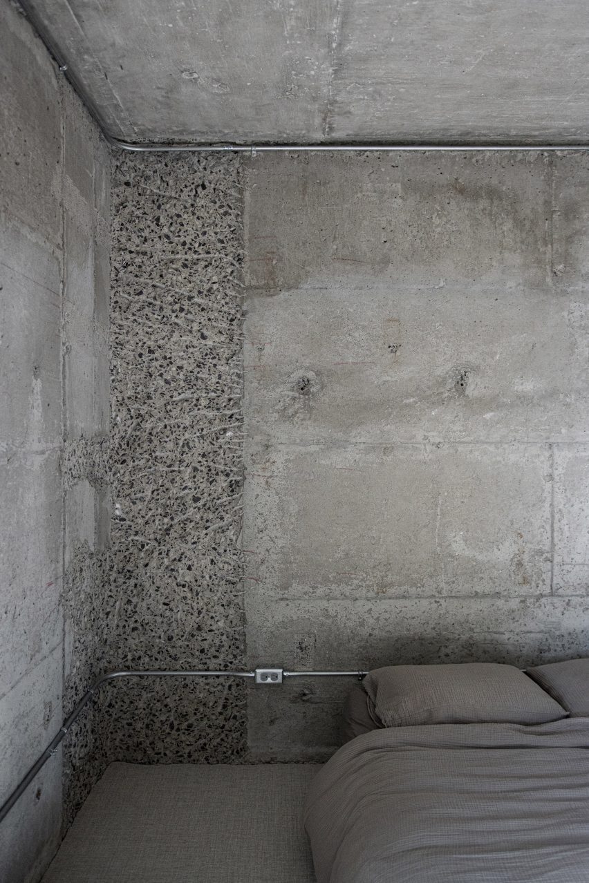 Concrete bedroom solely furnished with a low bed