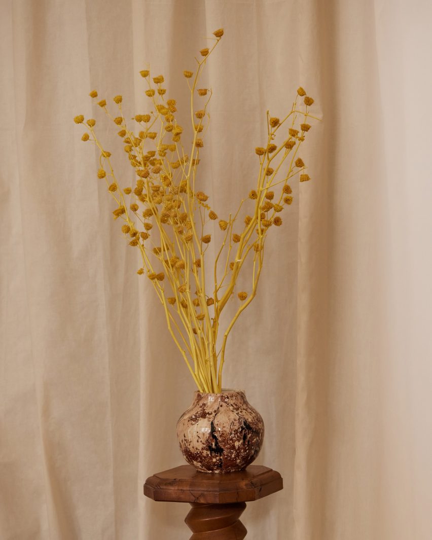 Vase on a wooden plinth with yellow blooms