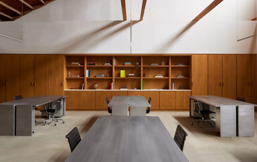 Communal workspace featuring aluminium desks atop a raw concrete floor