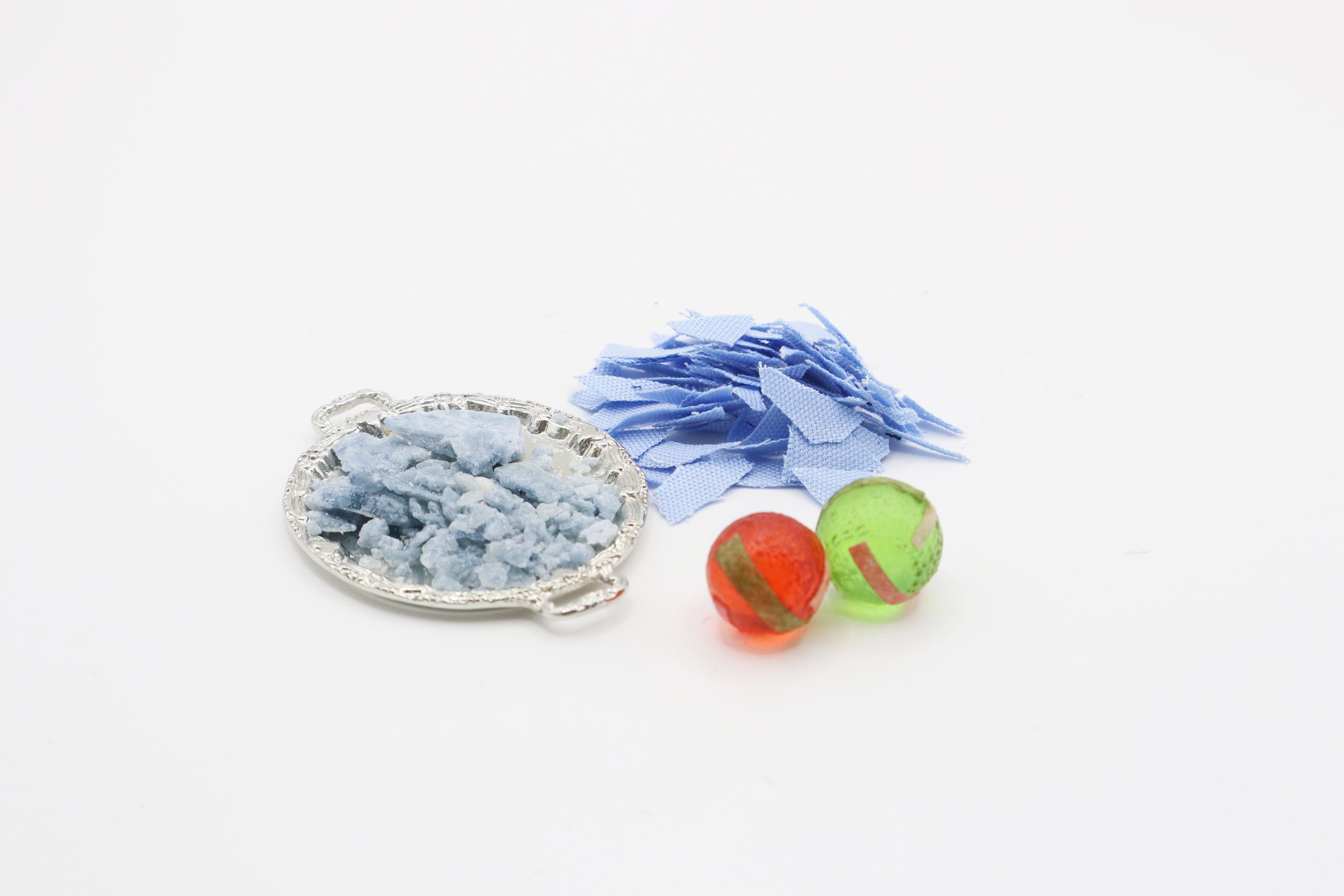 Photo of light blue fabric scraps beside two bright spherical hard candies by Jinghan Li