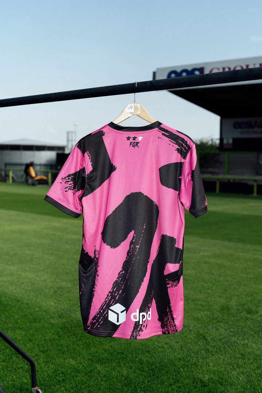 Pink football shirt on hanger above grass pitch