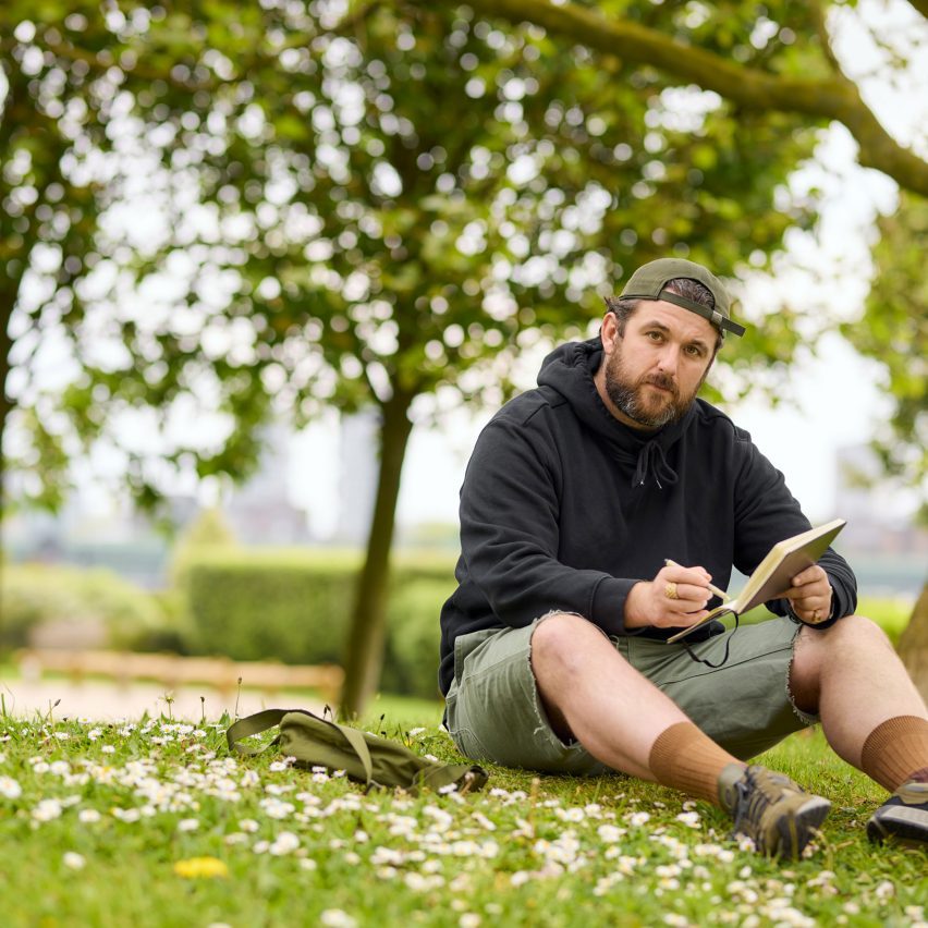 a photograph of a person holding a sketchbook in a green field