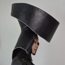 A photograph of a person wearing a large headpiece which is designed to collect rainwater