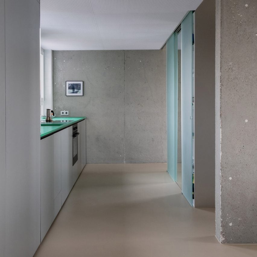 View into a plain kitchen with a concrete wall at the far end