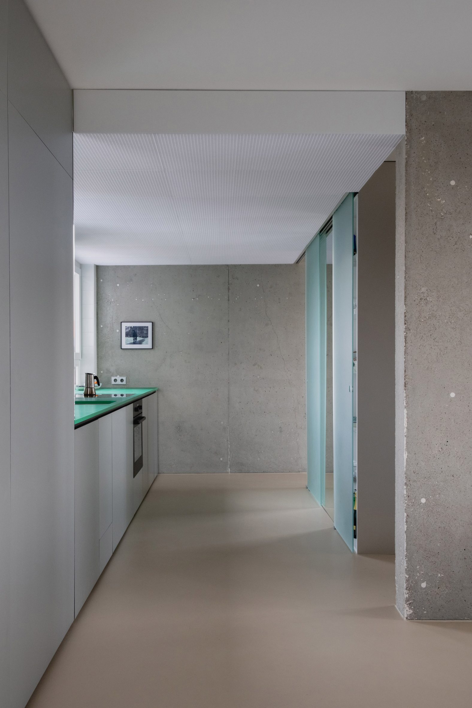 View into a plain kitchen with a concrete wall at the far end