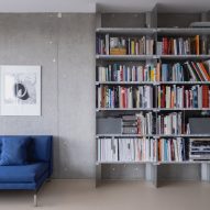 Bookcase and blue sofa in living area with concrete walls