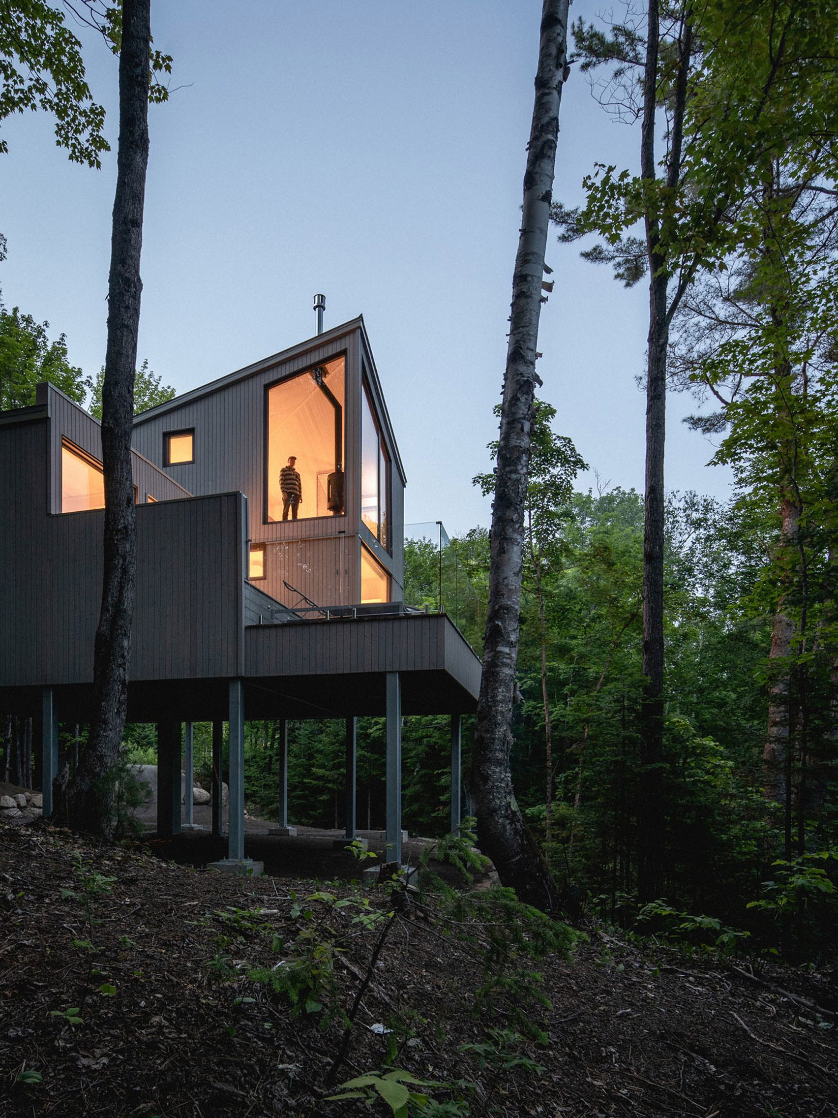 Cabin-like holiday home raised on stilts in Canadian woodland