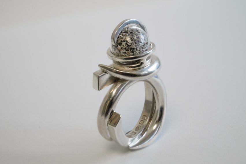 Photo of a ring with a thick silver band and a complex looped setting holding a sphere of dust