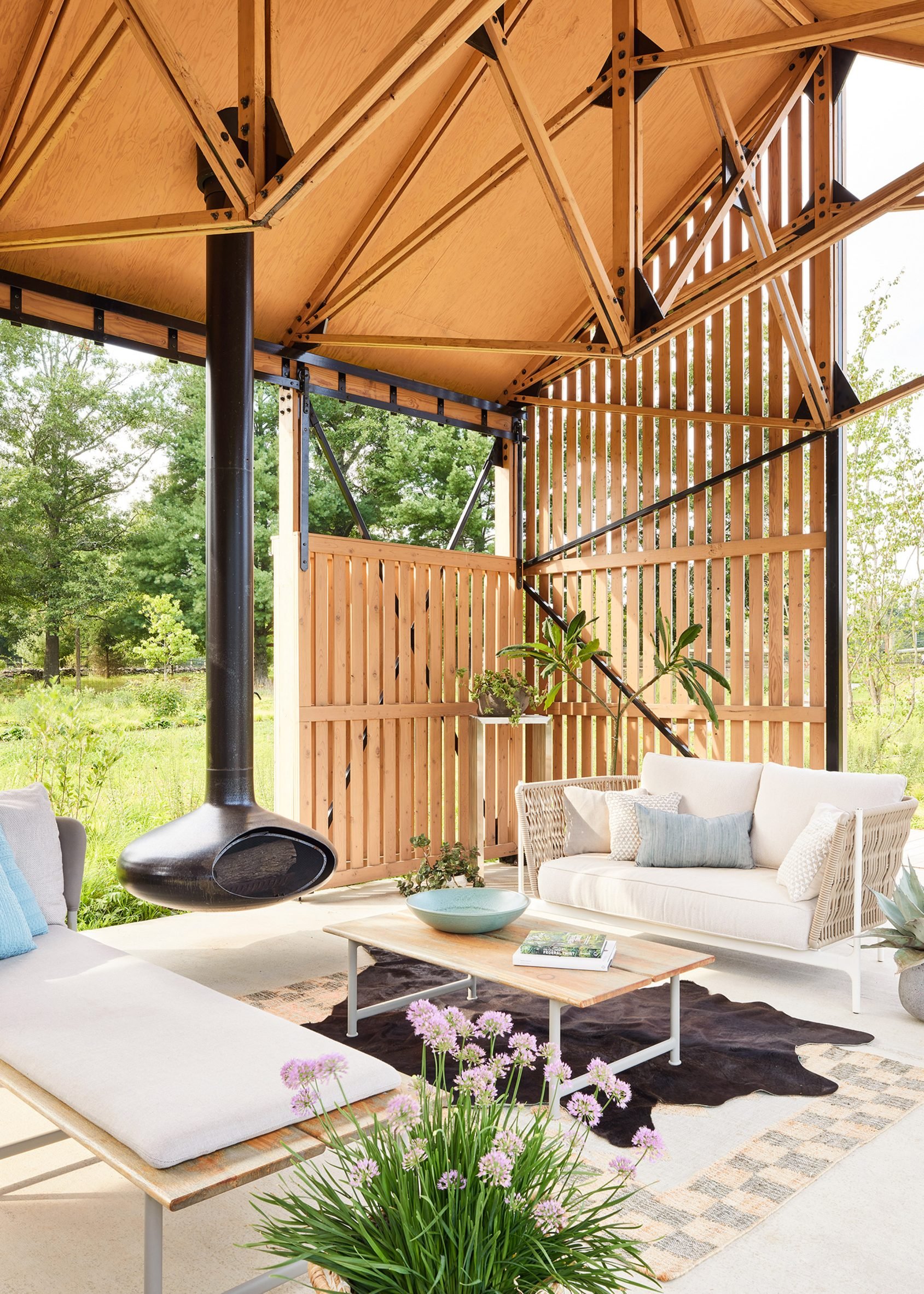 A lounge space with a black fireplace suspended from the roof