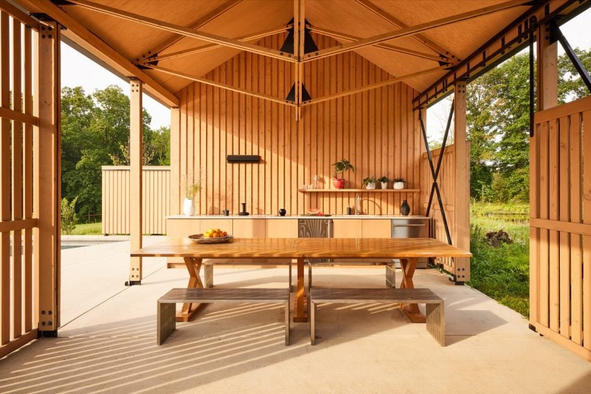 Pool house interior with a kitchen at the far end and a dining area in the centre