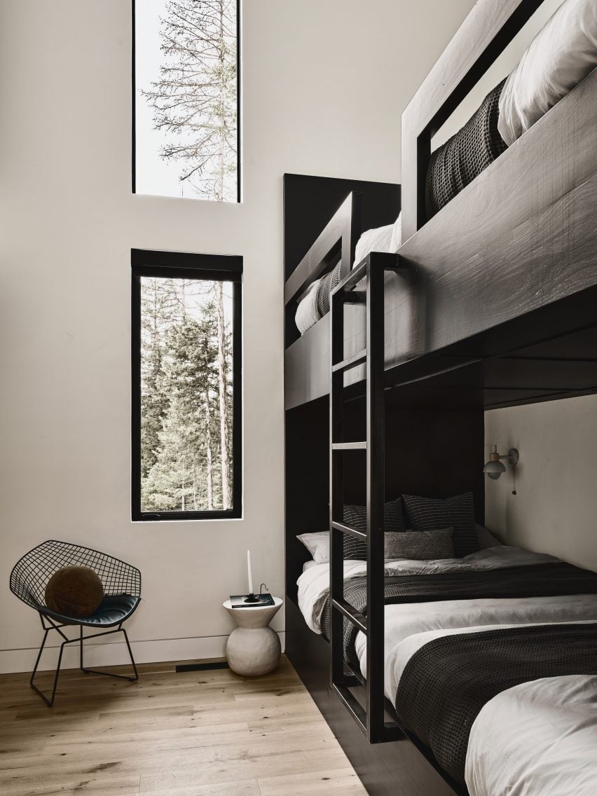 Black wooden bunkbeds in white wall room with stacked windows