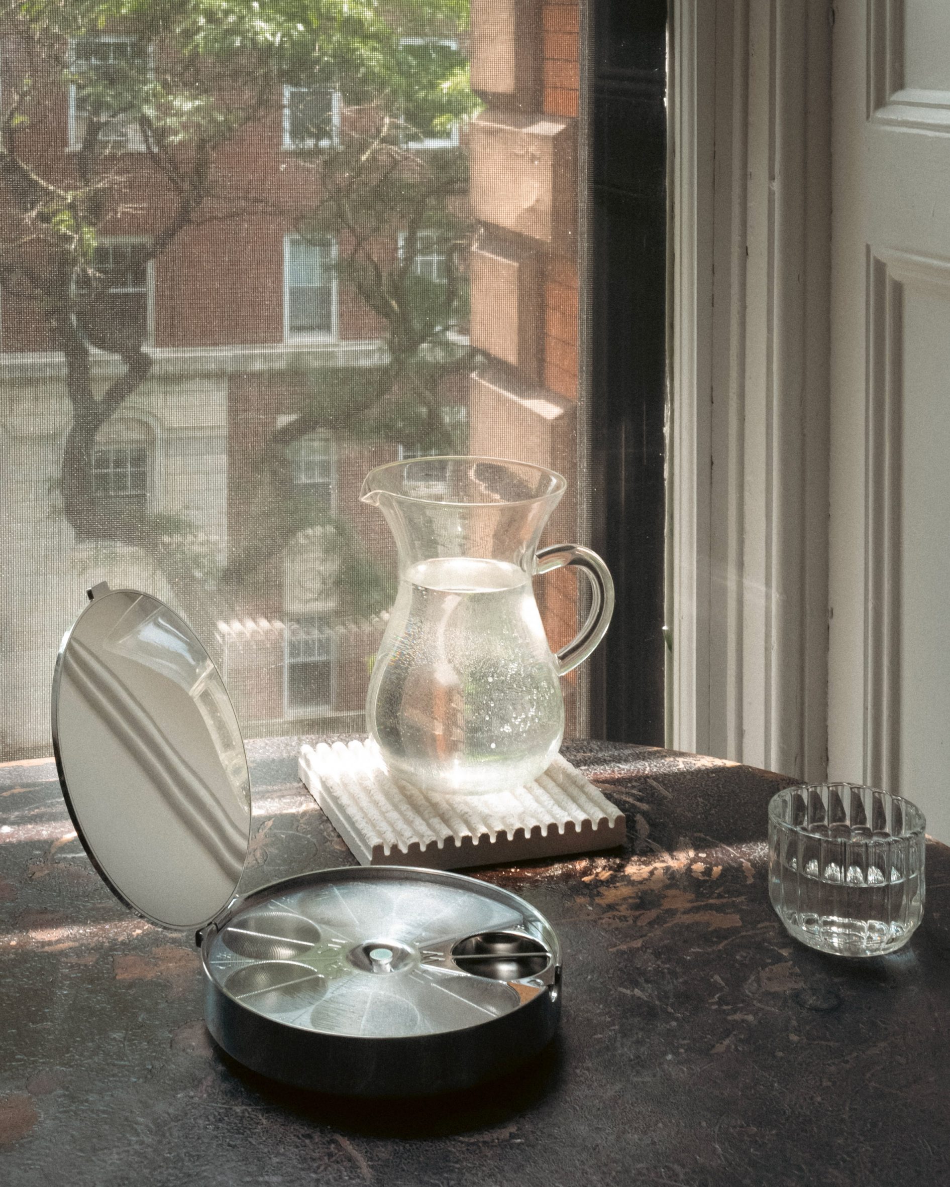 A metal pill contain sitting in front of window