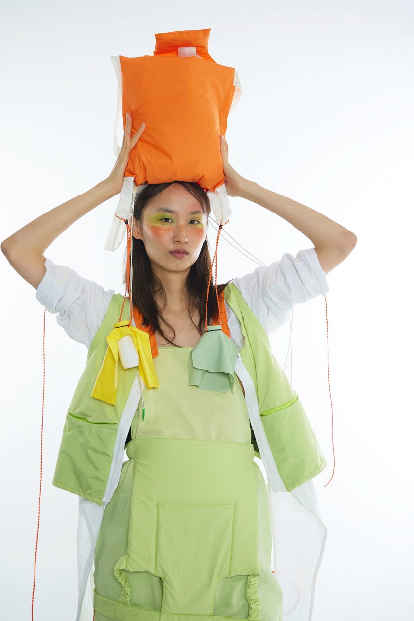 Model wearing 'Interdependence' and holding up baby carrier for Infinity Women by Siyuan Liu