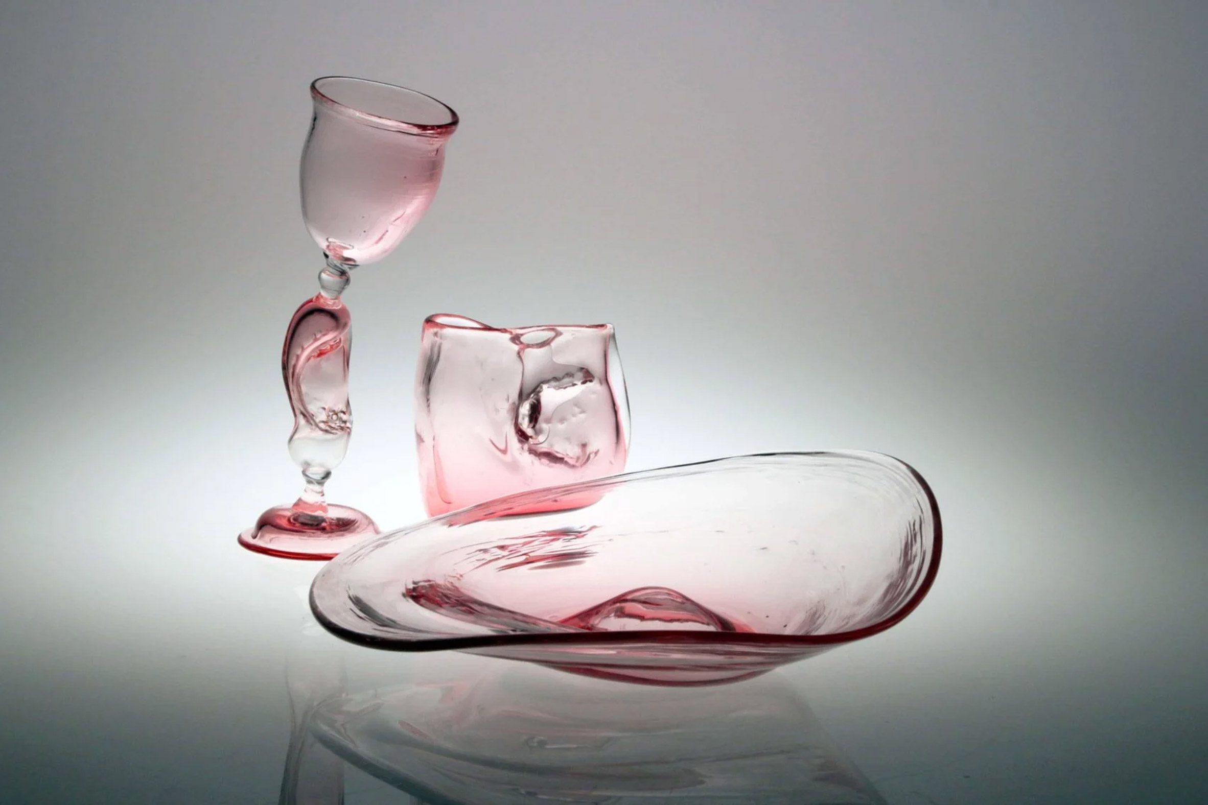 A photograph of a pink glassware collection in abstract circular forms.