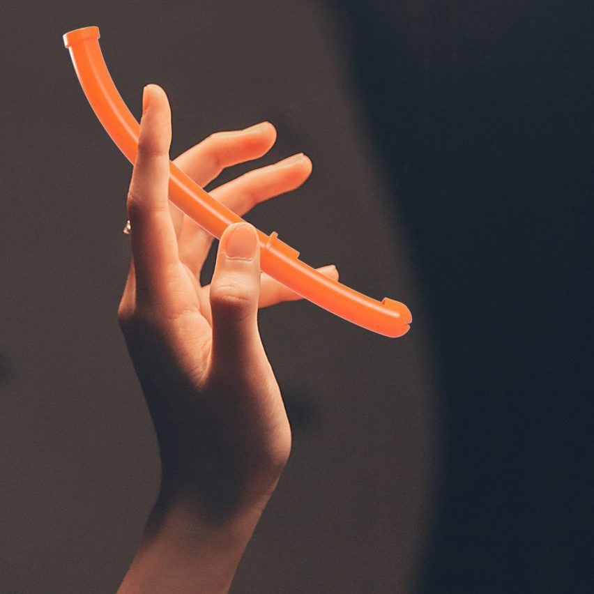 A photograph of a person's hand holding an orange curved tampon applicator.