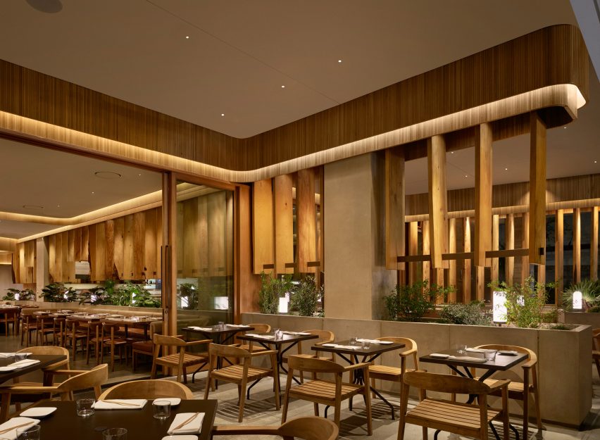 Custom-made concrete planters under wooden board partitions extend to a dining area on the terrace