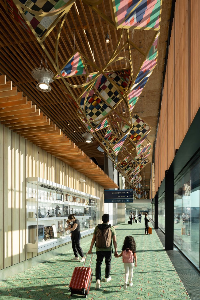 Child and father walking under art at Portland new airport terminal