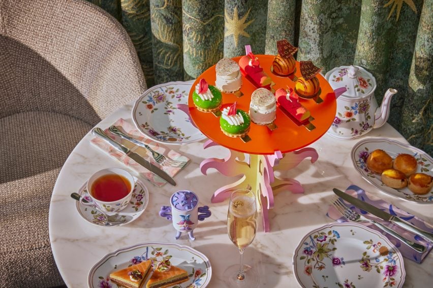 A photograph of an orange-coloured variation of the tea stand on the table with floral crockery.