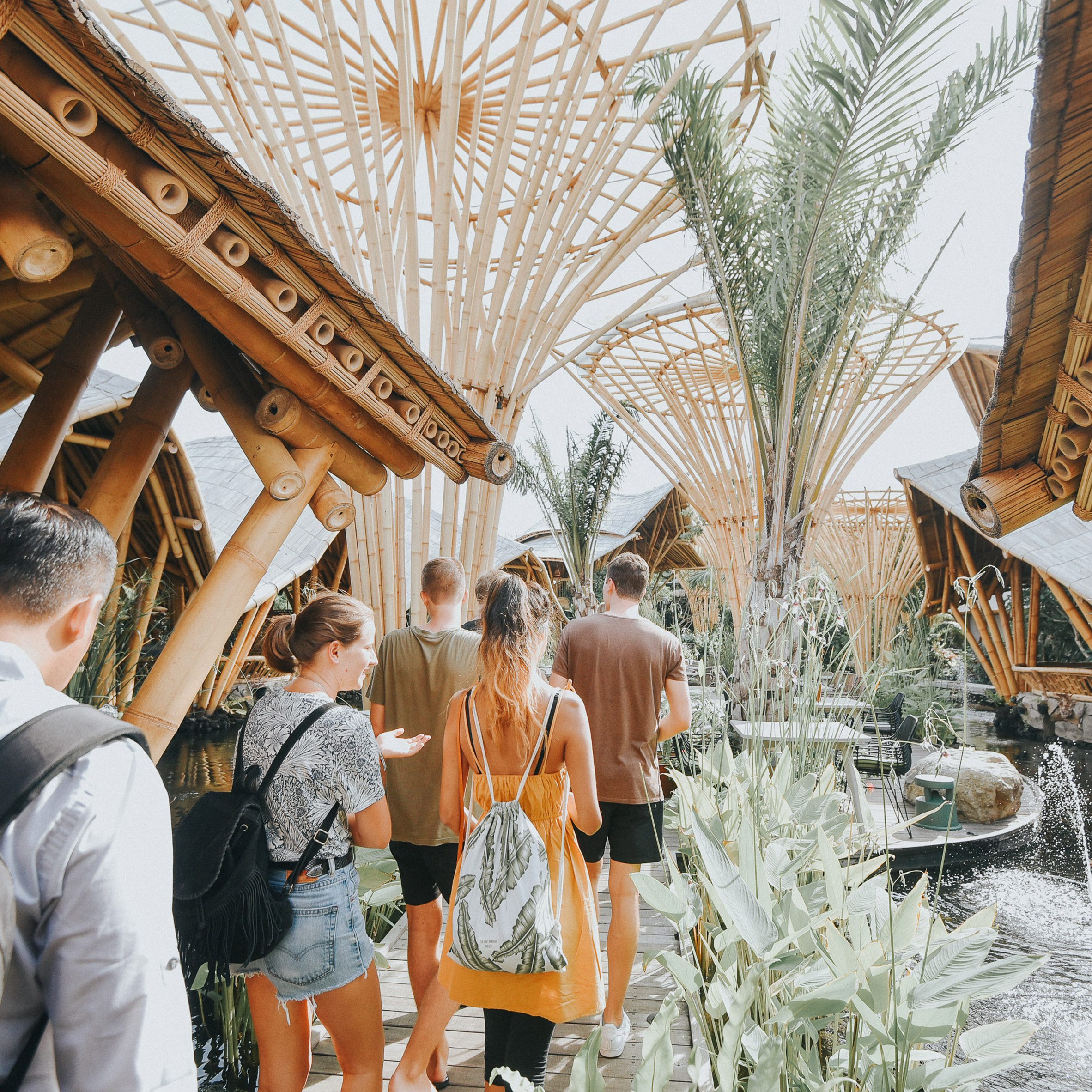 Students walking through a tropical garden with architectural bamboo structures.