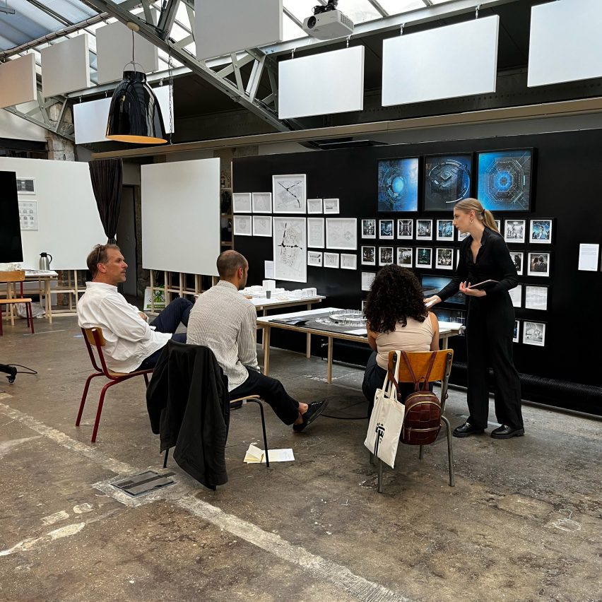 Photograph of students sitting around a table where work is being presented.