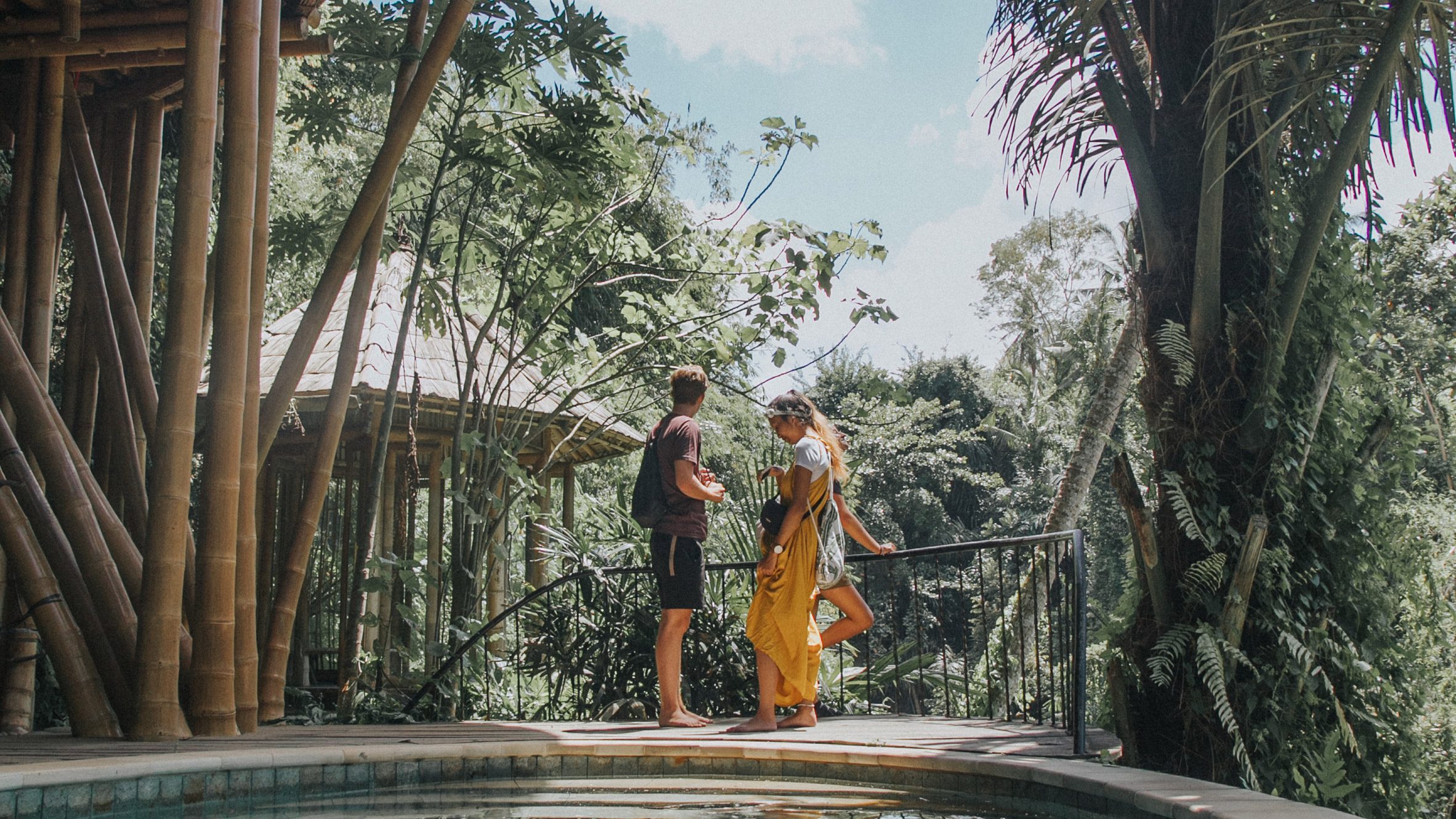 Photograph of two students conversing in a leafy, tropical setting.