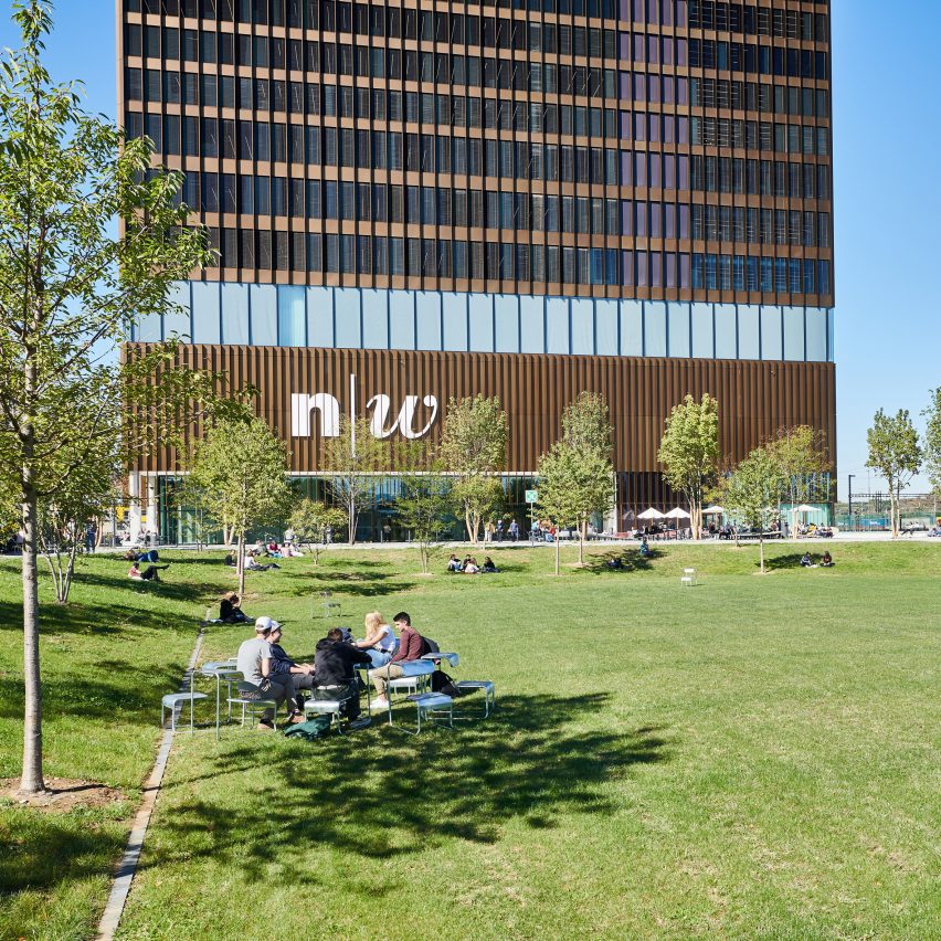 Photograph of students sitting on the common outside of a university building.