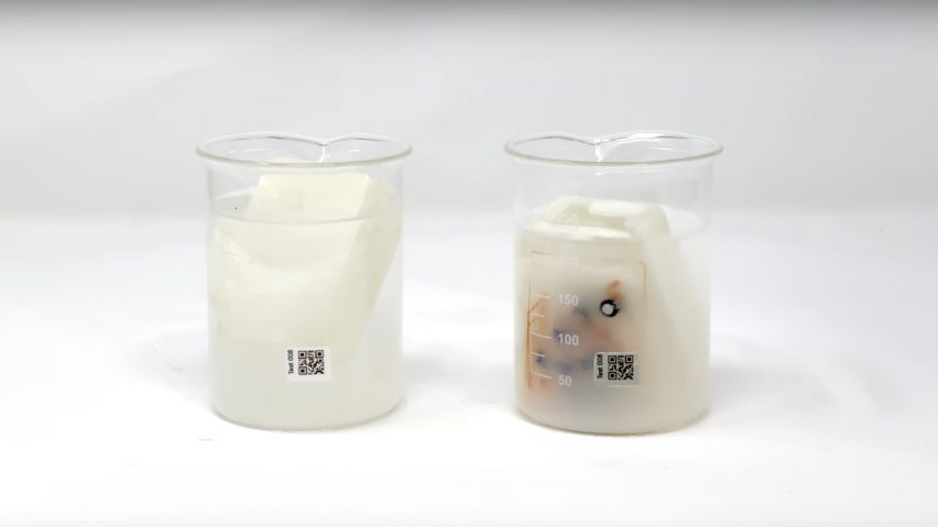 Photo of two beakers of liquid, the one on the left containing a solid white plastic case and the one on the left containing one that has been dismantled and is dissolving into mush