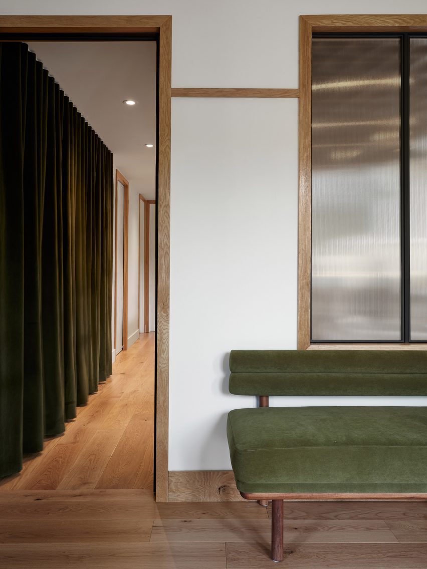 Green velvet bench beside a doorway leading to a corridor