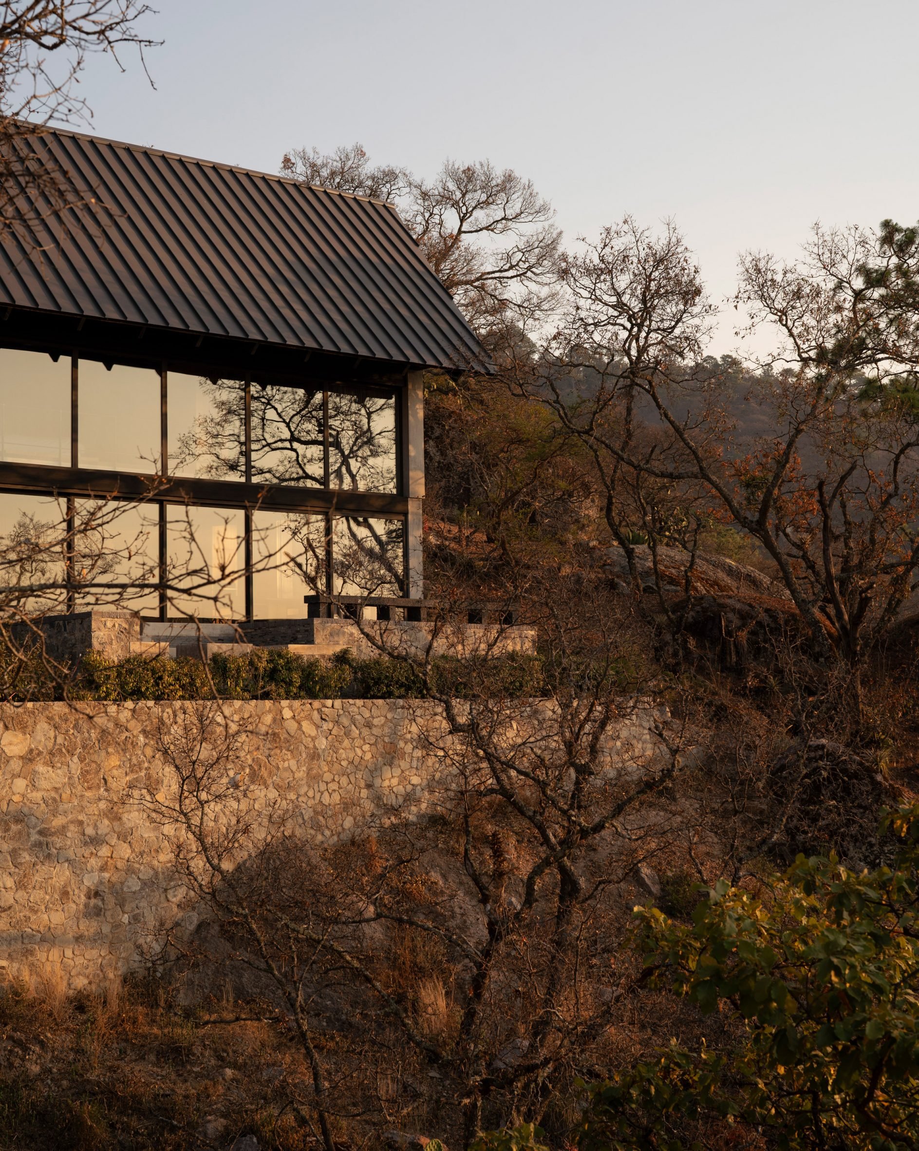 Glass walls of concrete home on brick retaining wall